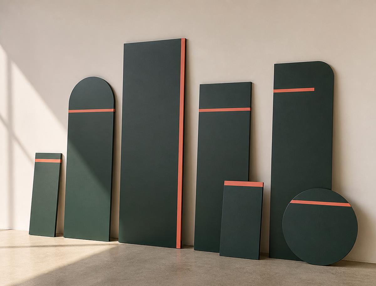 Deep green signage prototype panels with coral accent stripes leaning against an ivory wall